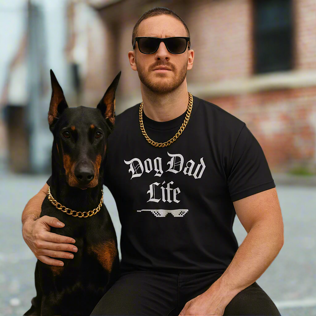 Man wearing a 'Dog Dad Life' shirt sitting with a dog in front of a building.