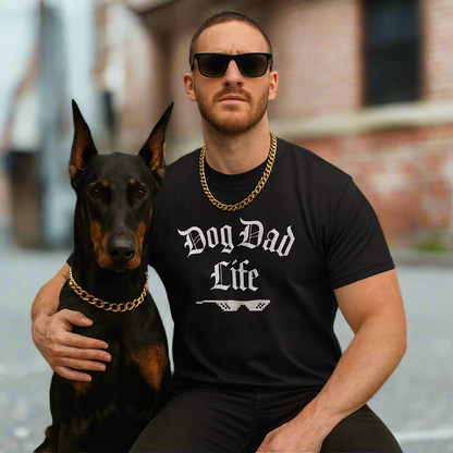 Man wearing a 'Dog Dad Life' shirt sitting with a dog in front of a building.