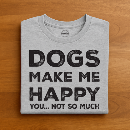 Folded gray t-shirt with 'DOGS MAKE ME HAPPY YOU... NOT SO MUCH' text on a wooden surface